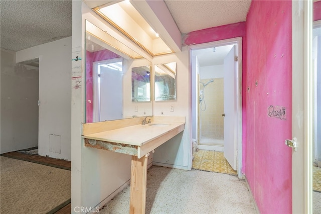 bathroom featuring a textured ceiling, a shower stall, toilet, and a sink