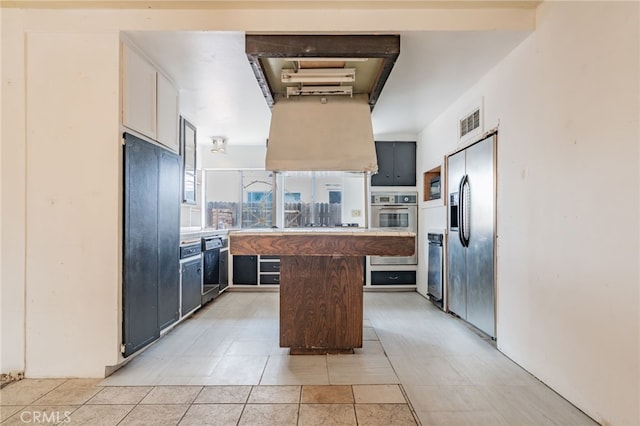 kitchen with visible vents, a kitchen island, black appliances, and light countertops