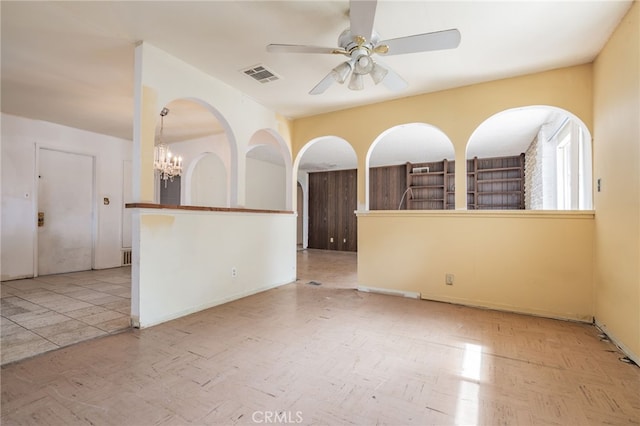 empty room featuring ceiling fan with notable chandelier and visible vents