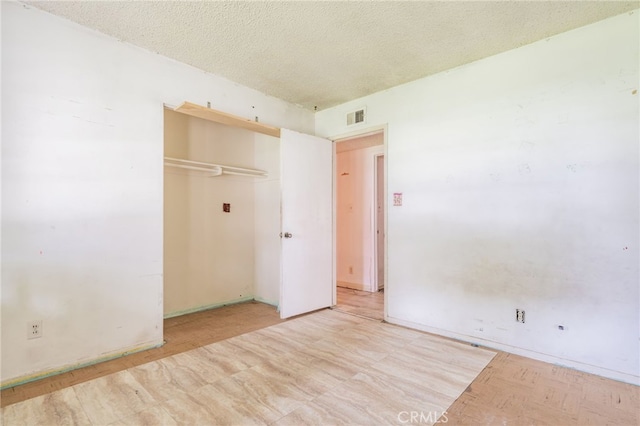 unfurnished bedroom featuring visible vents, a textured ceiling, and a closet