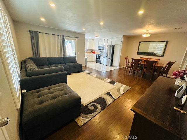 living room with hardwood / wood-style floors, visible vents, recessed lighting, and baseboards