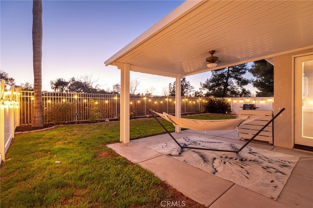 patio terrace at dusk featuring a lawn and a fenced backyard