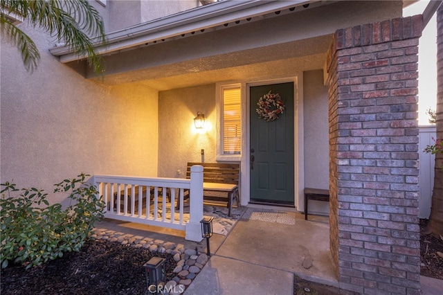 view of exterior entry with covered porch and stucco siding