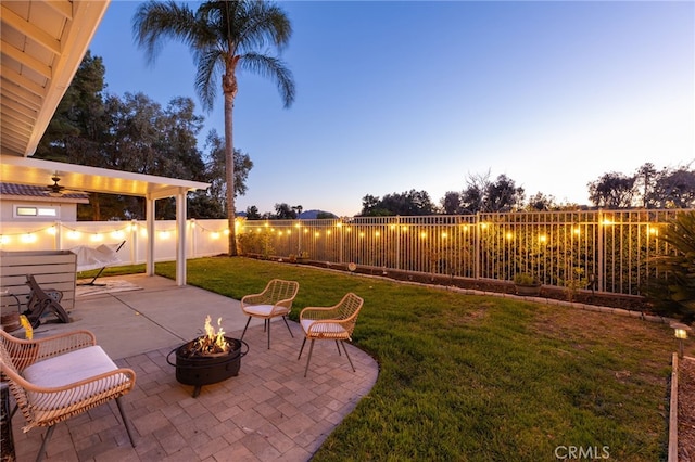 yard at dusk with a fire pit, a fenced backyard, and a patio area