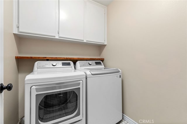 clothes washing area with baseboards, cabinet space, and washer and clothes dryer