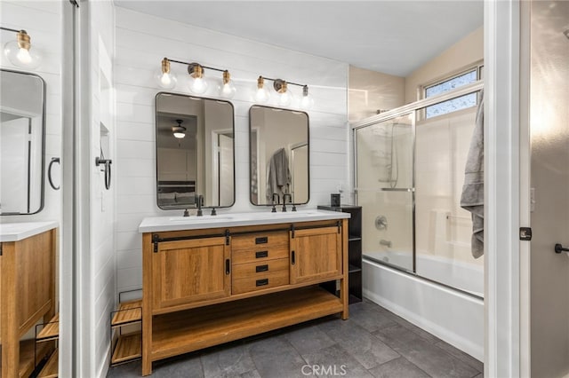 bathroom with double vanity, enclosed tub / shower combo, and a sink