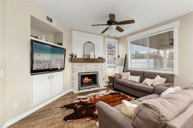 living area with visible vents, a fireplace with flush hearth, a ceiling fan, wood finished floors, and baseboards