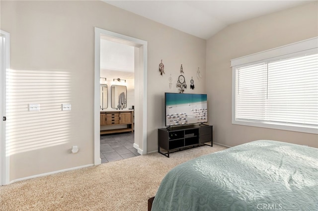 bedroom featuring vaulted ceiling, ensuite bath, baseboards, and carpet floors