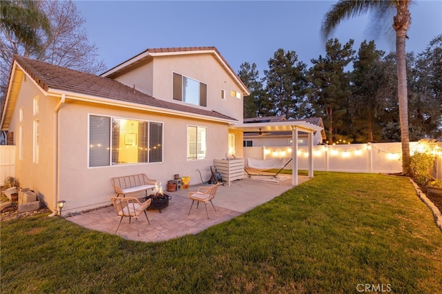 rear view of house featuring an outdoor fire pit, stucco siding, a yard, a fenced backyard, and a patio