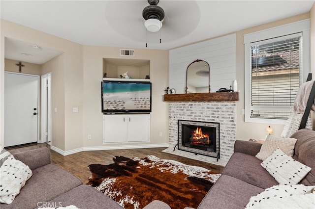 living room featuring baseboards, a fireplace, visible vents, and ceiling fan