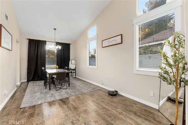 dining space with visible vents, wood finished floors, baseboards, a chandelier, and vaulted ceiling