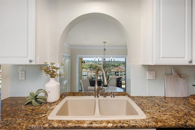 22364 Manacor Unit 9, Mission Viejo, CA 92692 - kitchen featuring a sink, arched walkways, white cabinetry, dark stone counters, and crown molding