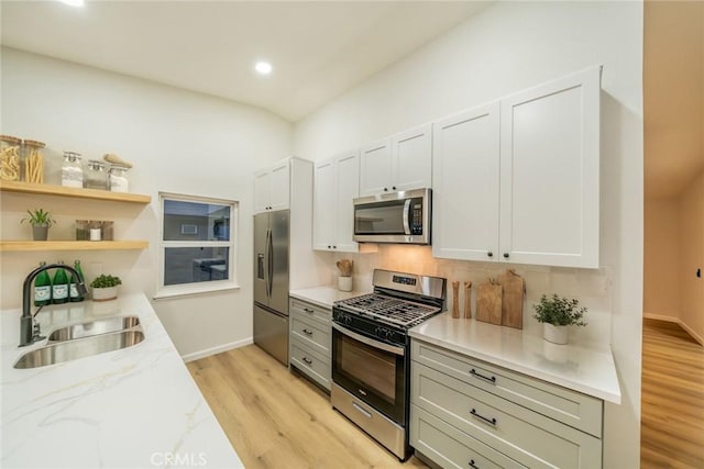 kitchen featuring light wood-style flooring, appliances with stainless steel finishes, open shelves, and a sink