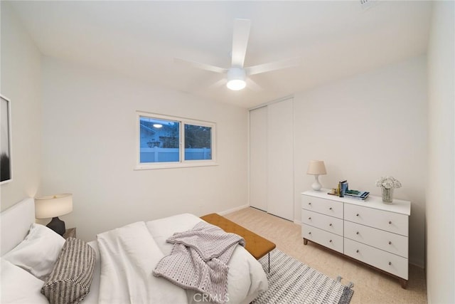 bedroom with a closet, light carpet, and a ceiling fan