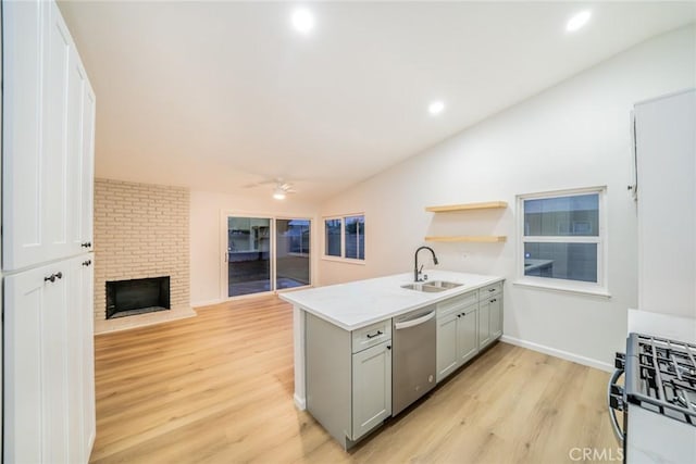 kitchen with gray cabinetry, lofted ceiling, range with gas stovetop, stainless steel dishwasher, and a sink