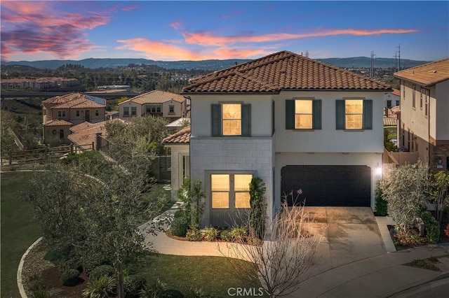 mediterranean / spanish house with fence, concrete driveway, a tile roof, an attached garage, and stucco siding