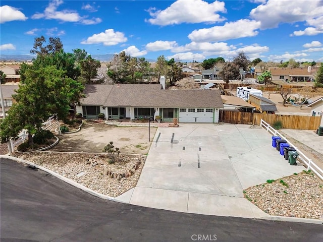 single story home with concrete driveway, an attached garage, fence, and a residential view