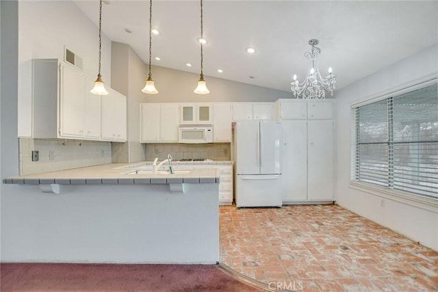 kitchen with white appliances, visible vents, a peninsula, tile counters, and white cabinets