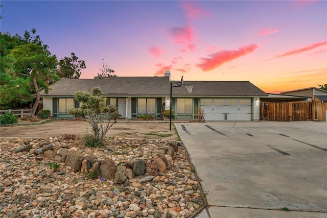 ranch-style house featuring concrete driveway, an attached garage, and fence