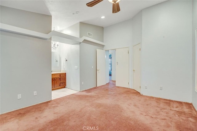 unfurnished bedroom featuring visible vents, connected bathroom, light carpet, high vaulted ceiling, and a ceiling fan