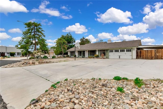 ranch-style house featuring concrete driveway, a garage, and fence