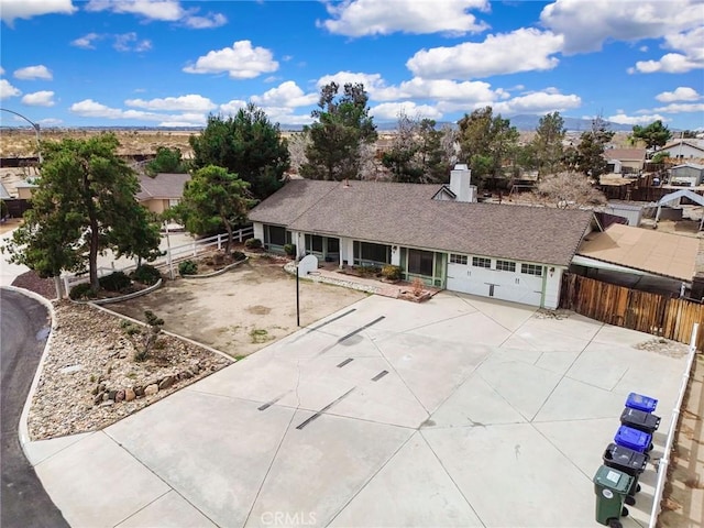 view of front of property featuring a shingled roof, an attached garage, concrete driveway, and fence