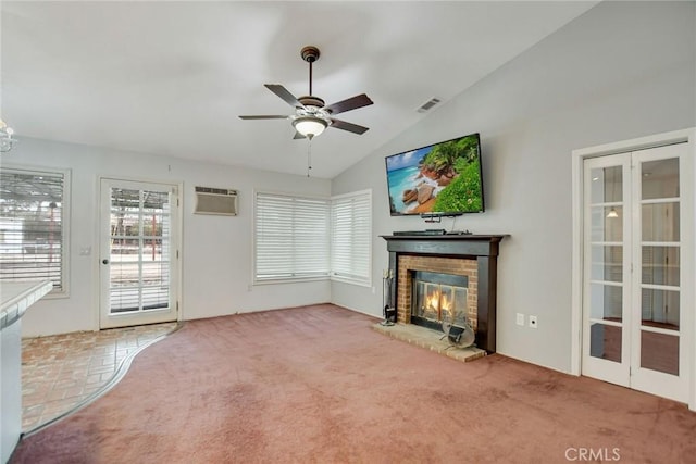 unfurnished living room with visible vents, a brick fireplace, carpet, a wall unit AC, and vaulted ceiling