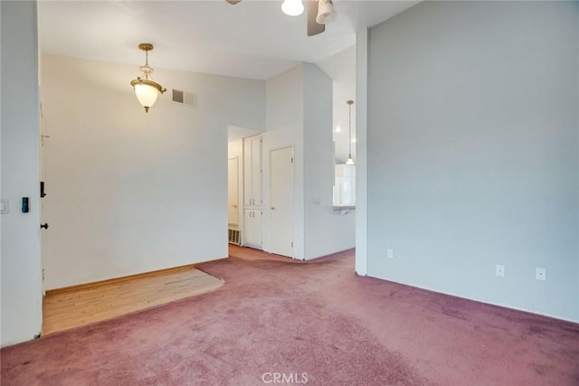 empty room featuring visible vents, carpet, ceiling fan, and vaulted ceiling