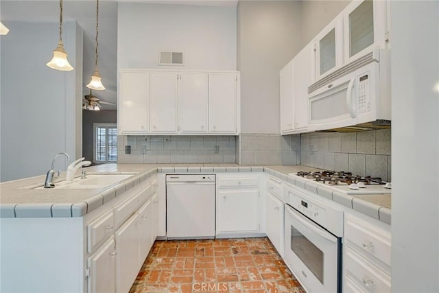 kitchen with a sink, visible vents, white appliances, and decorative backsplash