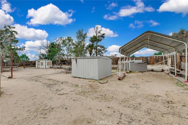 view of yard with a storage shed, a fenced backyard, a carport, and an outdoor structure