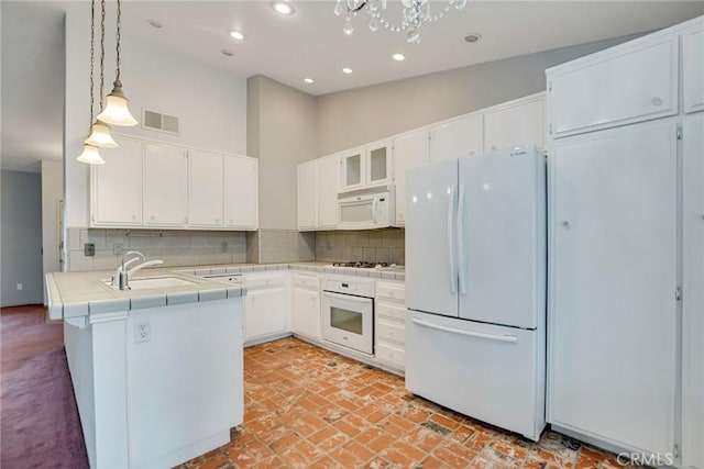 kitchen with tile countertops, visible vents, white appliances, and tasteful backsplash