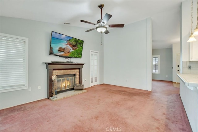 unfurnished living room featuring a ceiling fan, visible vents, lofted ceiling, a fireplace, and carpet flooring