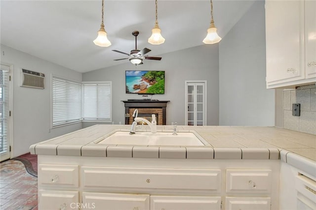 kitchen featuring lofted ceiling, tile counters, a fireplace, and brick floor