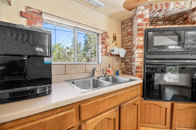 kitchen with tasteful backsplash, black appliances, light countertops, and a sink