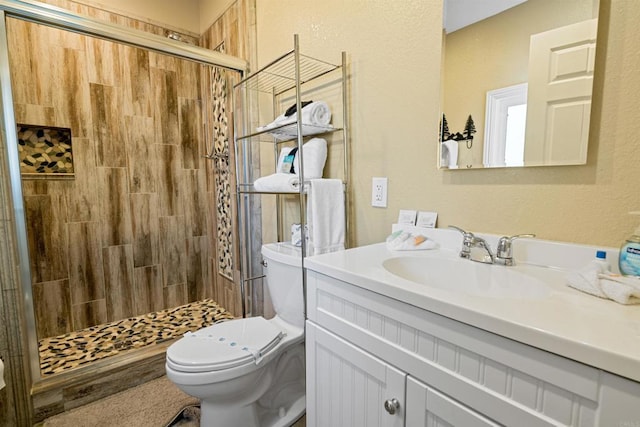 bathroom featuring a stall shower, toilet, and vanity