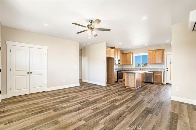 kitchen with stainless steel appliances, baseboards, a kitchen island, and wood finished floors