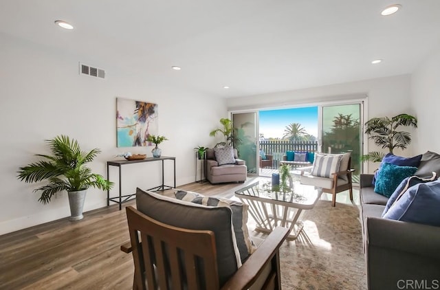 living room with recessed lighting, visible vents, baseboards, and wood finished floors