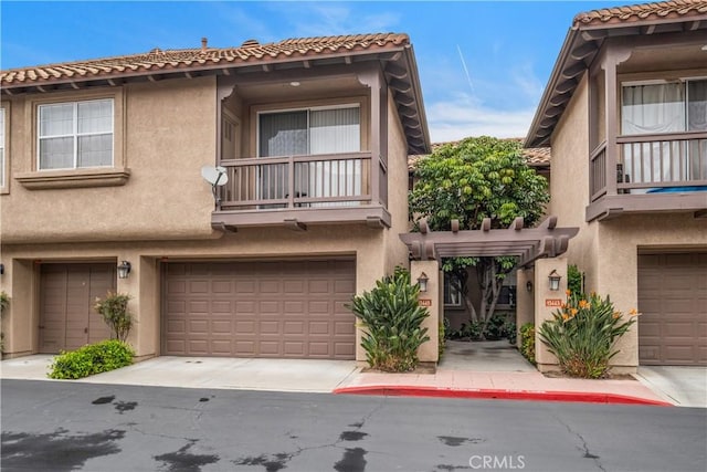 view of front of home featuring stucco siding, a tiled roof, and an attached garage