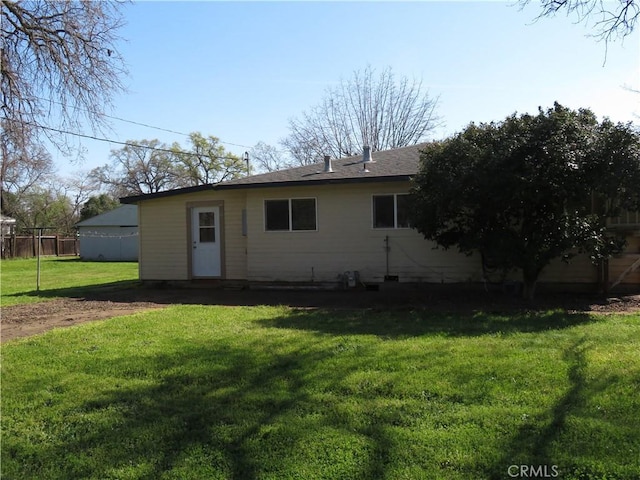 rear view of house featuring a lawn and fence