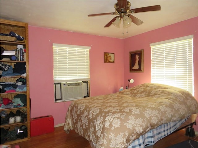 bedroom with cooling unit, wood finished floors, and ceiling fan