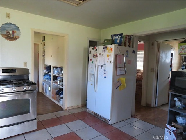 kitchen with visible vents, black microwave, stainless steel range with gas stovetop, white fridge with ice dispenser, and tile patterned floors