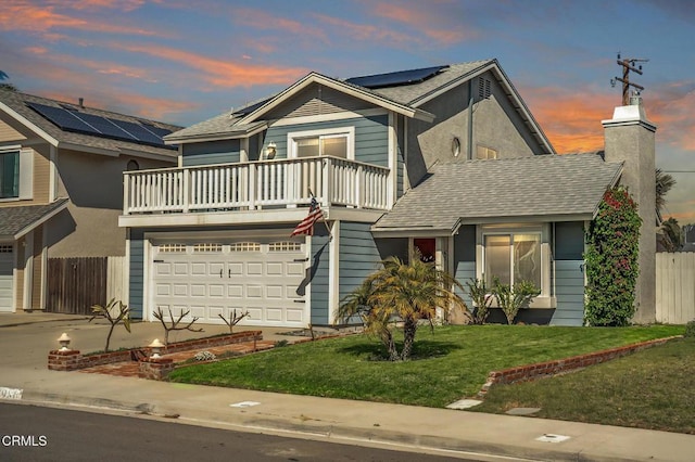 traditional home featuring roof mounted solar panels, fence, an attached garage, a shingled roof, and a front yard