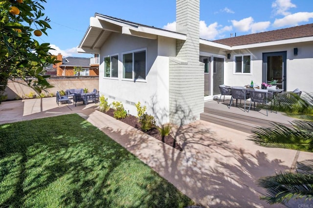 exterior space with stucco siding, a deck, a yard, an outdoor hangout area, and a chimney