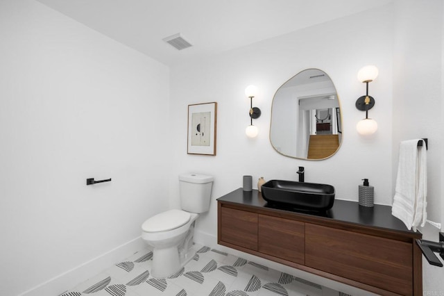 half bathroom with visible vents, baseboards, toilet, and vanity