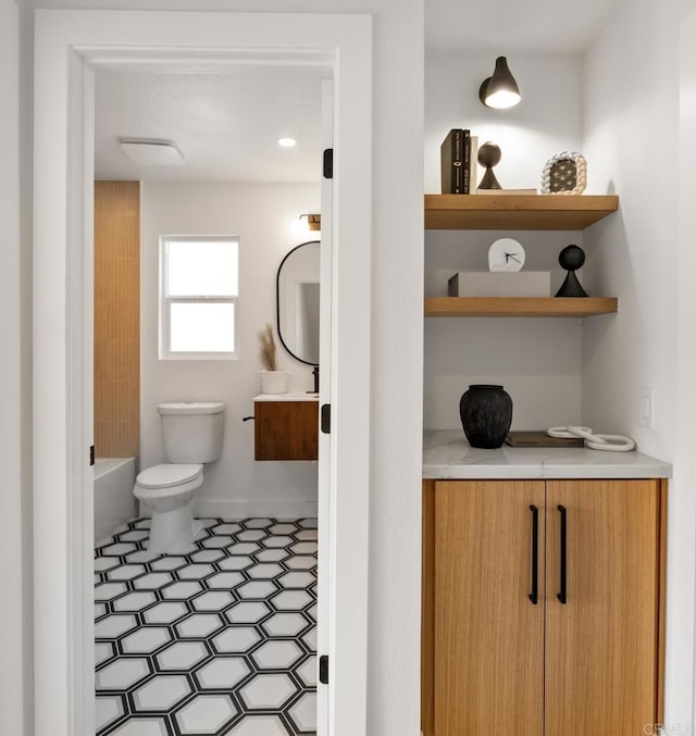 bathroom featuring vanity, a tub to relax in, baseboards, a shower, and toilet