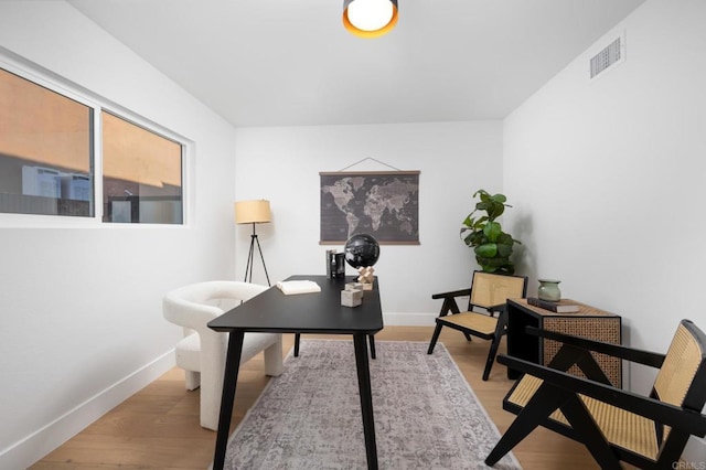 office space featuring light wood-type flooring, visible vents, and baseboards