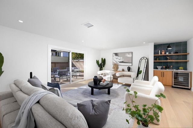 living room featuring beverage cooler, visible vents, wet bar, recessed lighting, and light wood-style floors