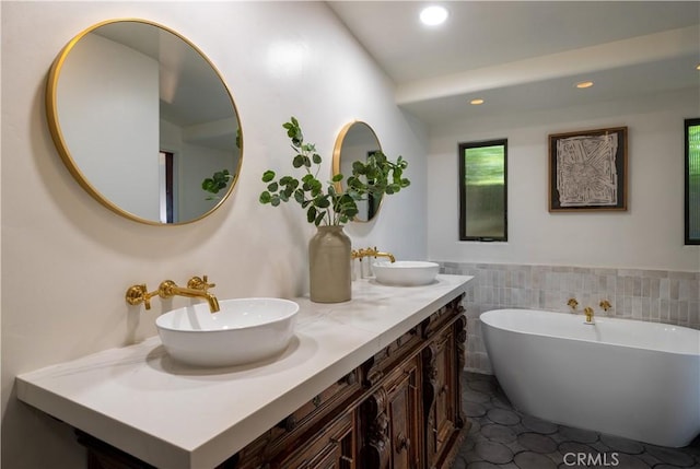 full bath featuring a sink, a freestanding tub, recessed lighting, and tile patterned floors