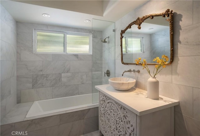 full bath with tile walls, vanity, and tiled shower / bath