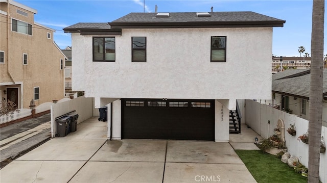 view of front of house with an attached garage, fence, stairway, stucco siding, and driveway